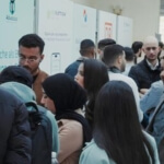 Eine Gruppe von Menschen vor den Messeständen auf der Fachkräftemesse in Tunis