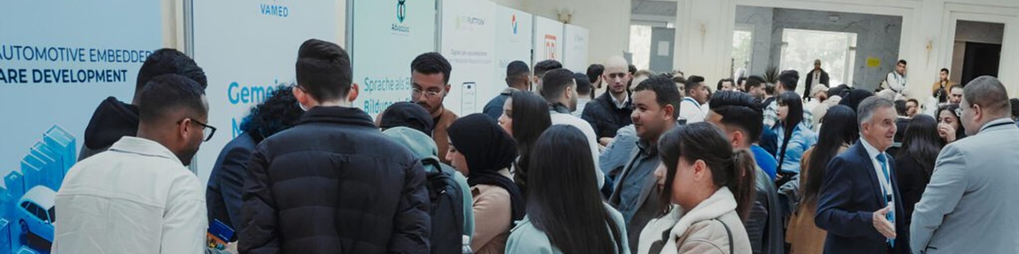 Eine Gruppe von Menschen vor den Messeständen auf der Fachkräftemesse in Tunis